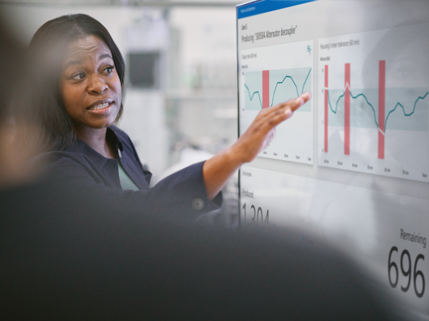 A person presenting a chart on a large screen to colleagues.